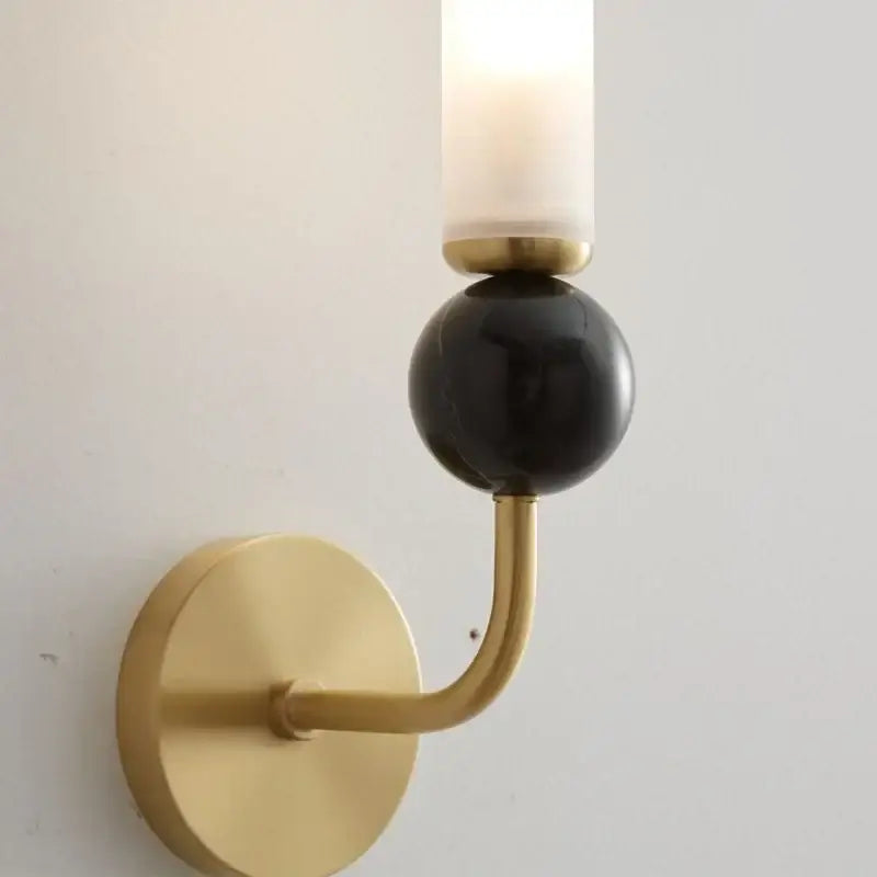 Modern wall lamp with gold-toned copper base, matte black accent, and frosted glass shade for living room decor