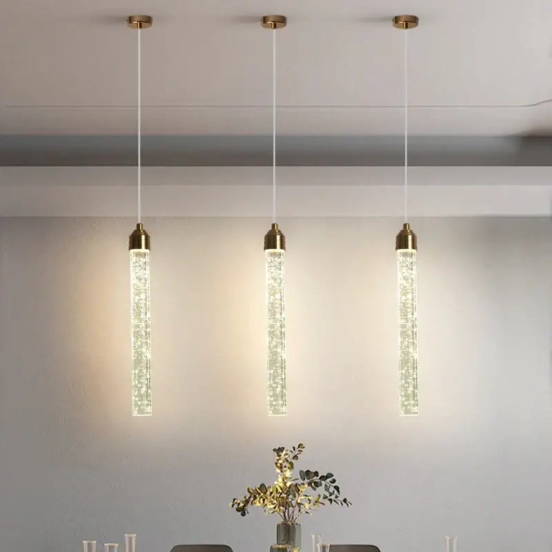 Three elegant gold-toned bubble crystal pendant lights with vertical tubes for modern dining room lighting