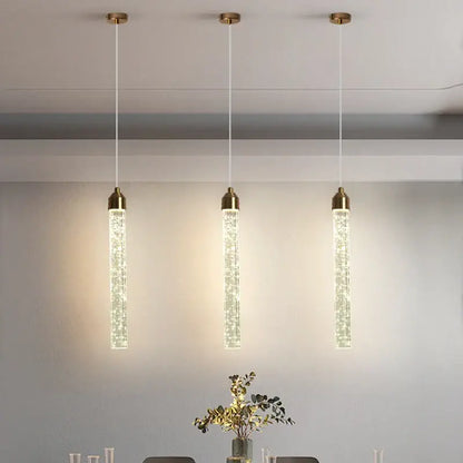 Three elegant gold-toned bubble crystal pendant lights with vertical tubes for modern dining room lighting