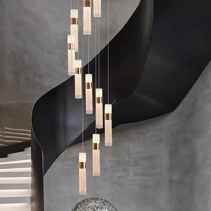 Modern gold pendant light with clear glass cylinders and brushed brass accents in adjustable height cascading design