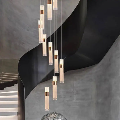 Modern gold pendant light with clear glass cylinders and brushed brass accents in adjustable height cascading design