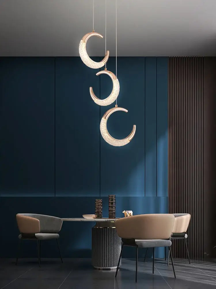 Three elegant gold crescent pendant lights with high-quality french metal crystal finish for dining settings