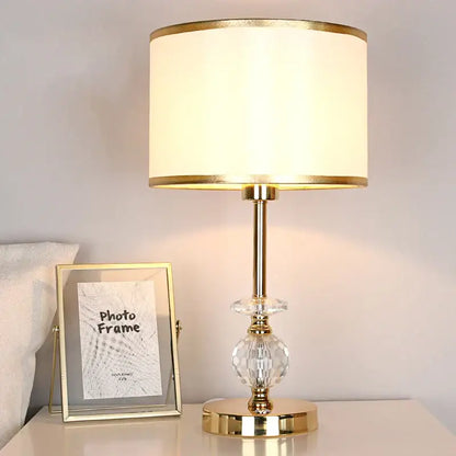 Modern gold crystal ball table lamp with a cream fabric shade and faceted crystal accent for bedroom use