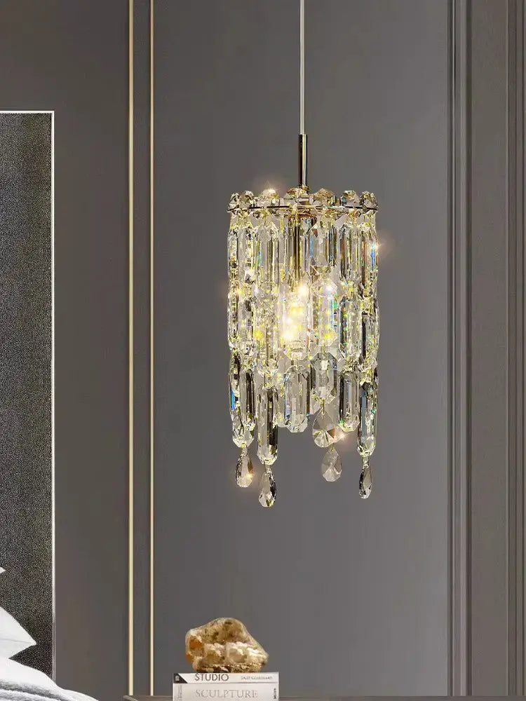 Modern gold crystal bedhead pendant light with cylindrical faceted prisms and warm glow for bedroom decorbites crystal bedhead