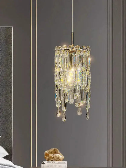 Modern gold crystal bedhead pendant light with cylindrical faceted prisms and warm glow for bedroom decorbites crystal bedhead