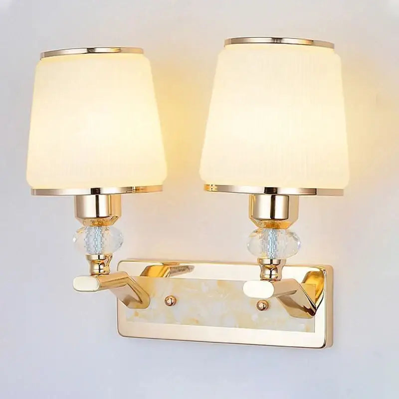Modern gold crystal bedside wall sconce with two cream fabric shades and bead accents for bedroom lighting