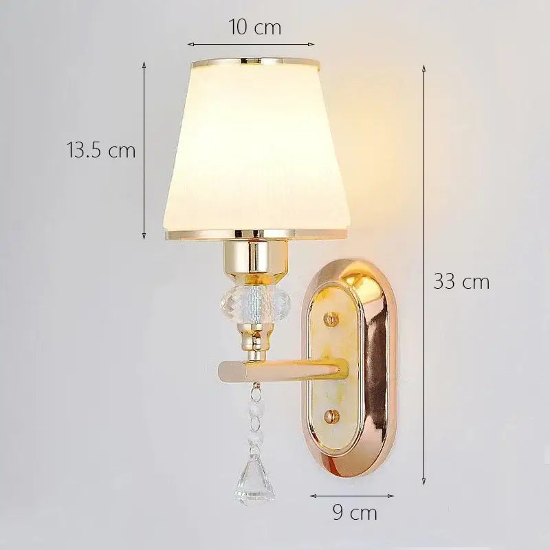 Modern gold crystal bedside wall sconce with fabric shade, ornate backplate, and cream-colored accents for bedroom decorbites crystal bedside wall