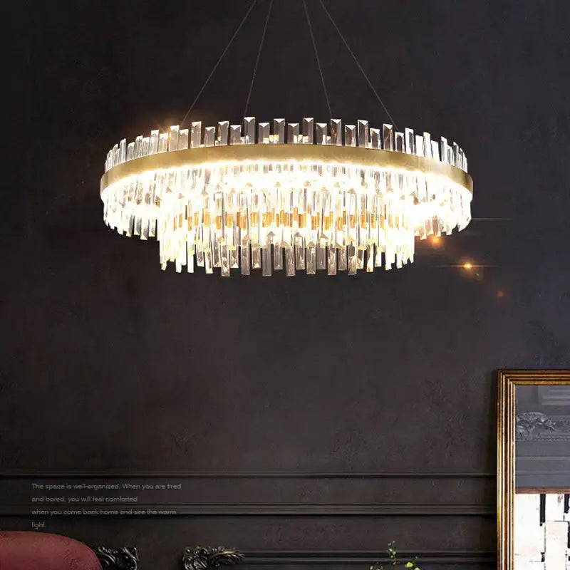 Modern gold crystal chandelier lighting fixture with a decorbites circular frame and cascading clear crystal prisms for dining room