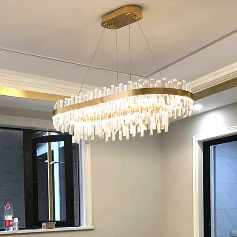 Modern gold crystal chandelier lighting fixture with gold-toned oval frame and cascading clear crystal rods decorbites circular