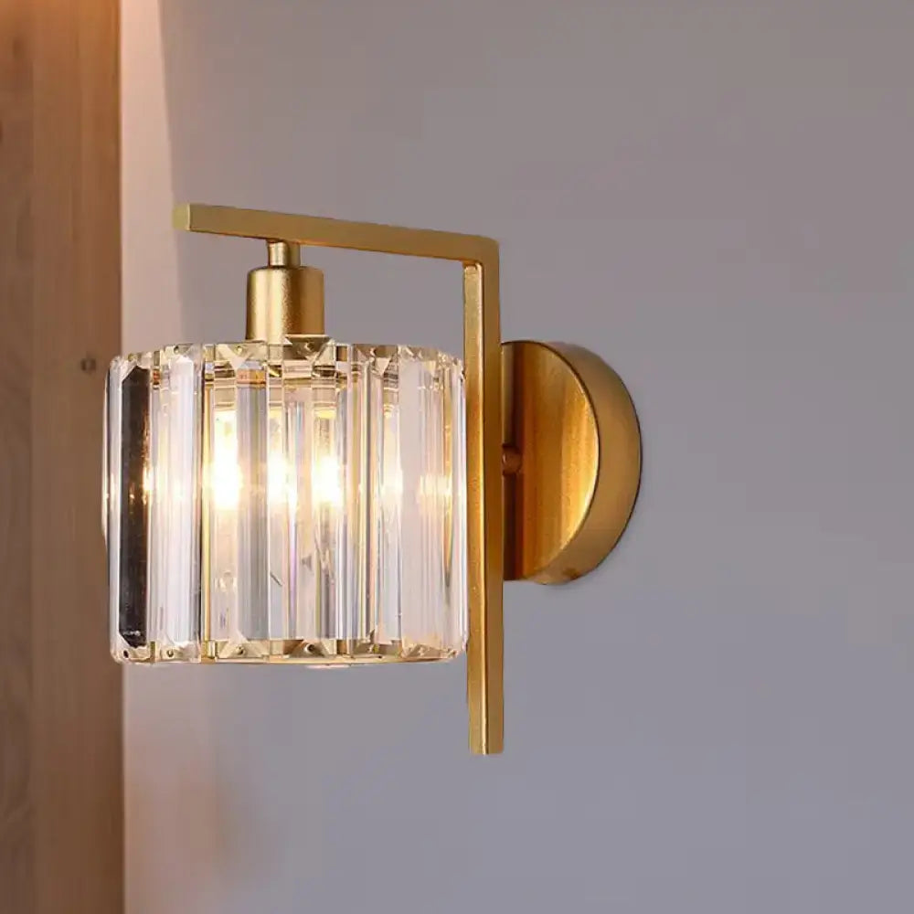 Modern gold wall sconce with cylindrical crystal glass shade featuring vertical facets ideal for bedroom light