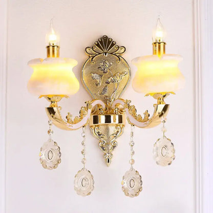 Modern gold wall mount light featuring ornate design with frosted glass shades and crystal droplet accents for bedroom use