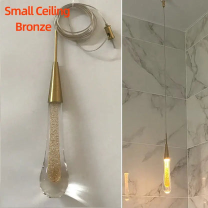 A small bronze pendant light with teardrop decorbites crystal glass led shade filled with golden glitter for dining room