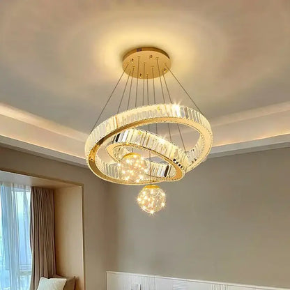 Modern gold pendant light with multiple crystal rings and dangling spheres in brushed stainless finish for dining room