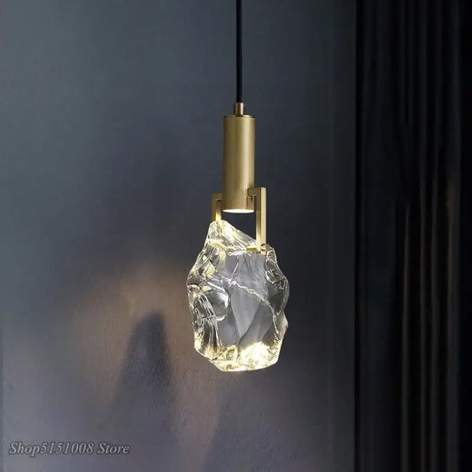 A modern gold crystal pendant light with an irregular clear glass shade emitting warm dining room illumination