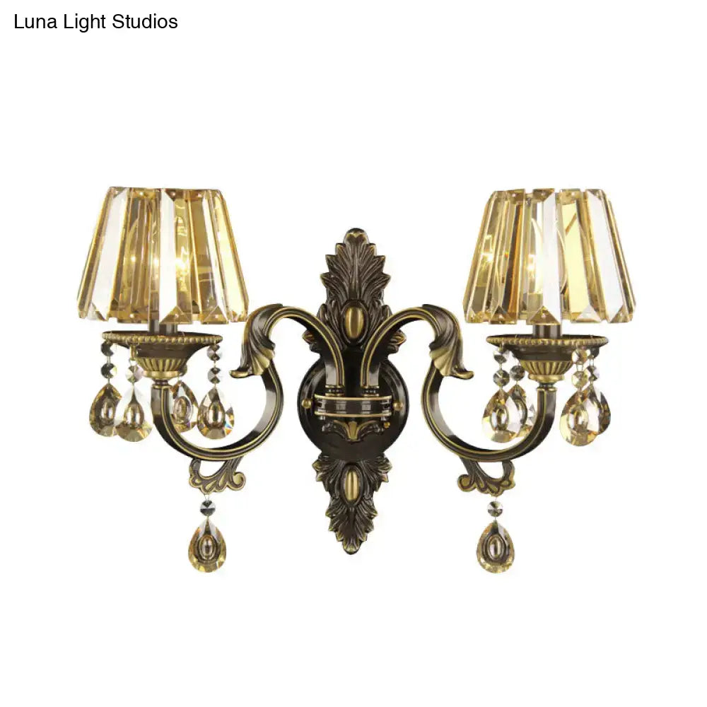 Antique brass two-light wall sconce with faceted amber glass and crystal teardrop pendants for living room lighting