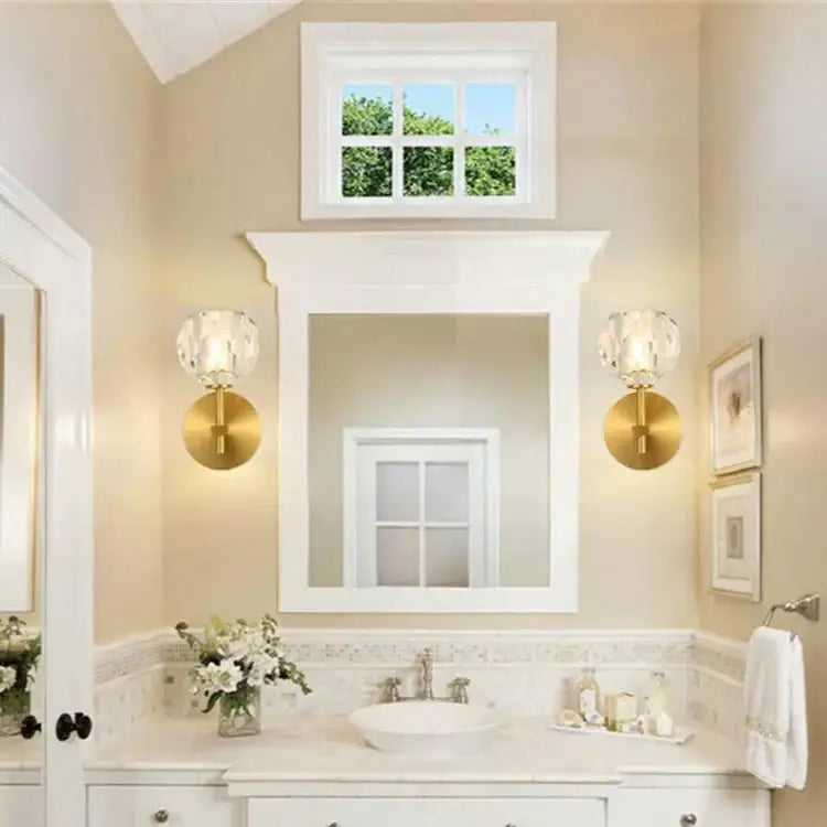 Gold finished DecorBites™ Ivy crystal wall lamps with faceted shades flank a white framed mirror in bathroom
