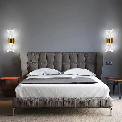 Modern gold crystal wall lamp with sculptural glass design above gray tufted velvet bed with white linens and dark gray throw blanket decorbites crystal wall lamp