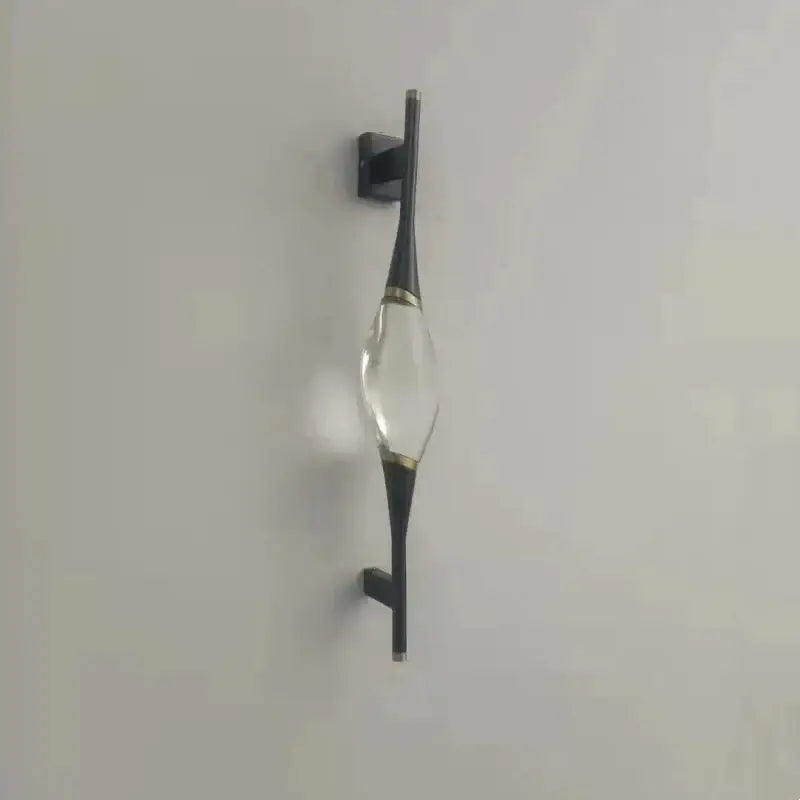 A modern gold crystal wall sconce with a clear crystal centerpiece and black metal arms for bedroom decorbites crystal wall use