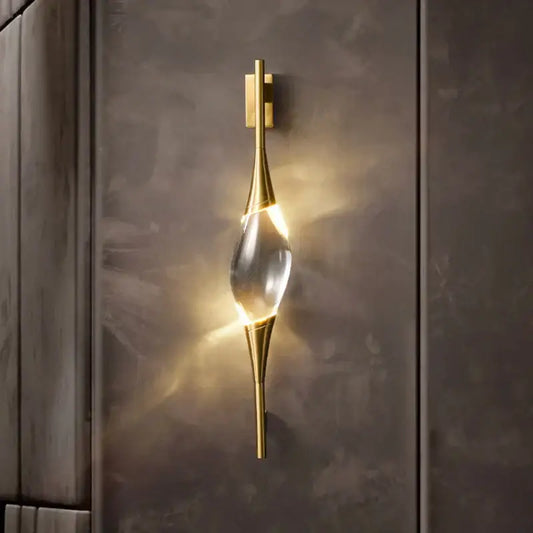 Modern gold crystal wall sconce with a clear teardrop centerpiece emitting warm light for bedroom decorbites crystal wall use