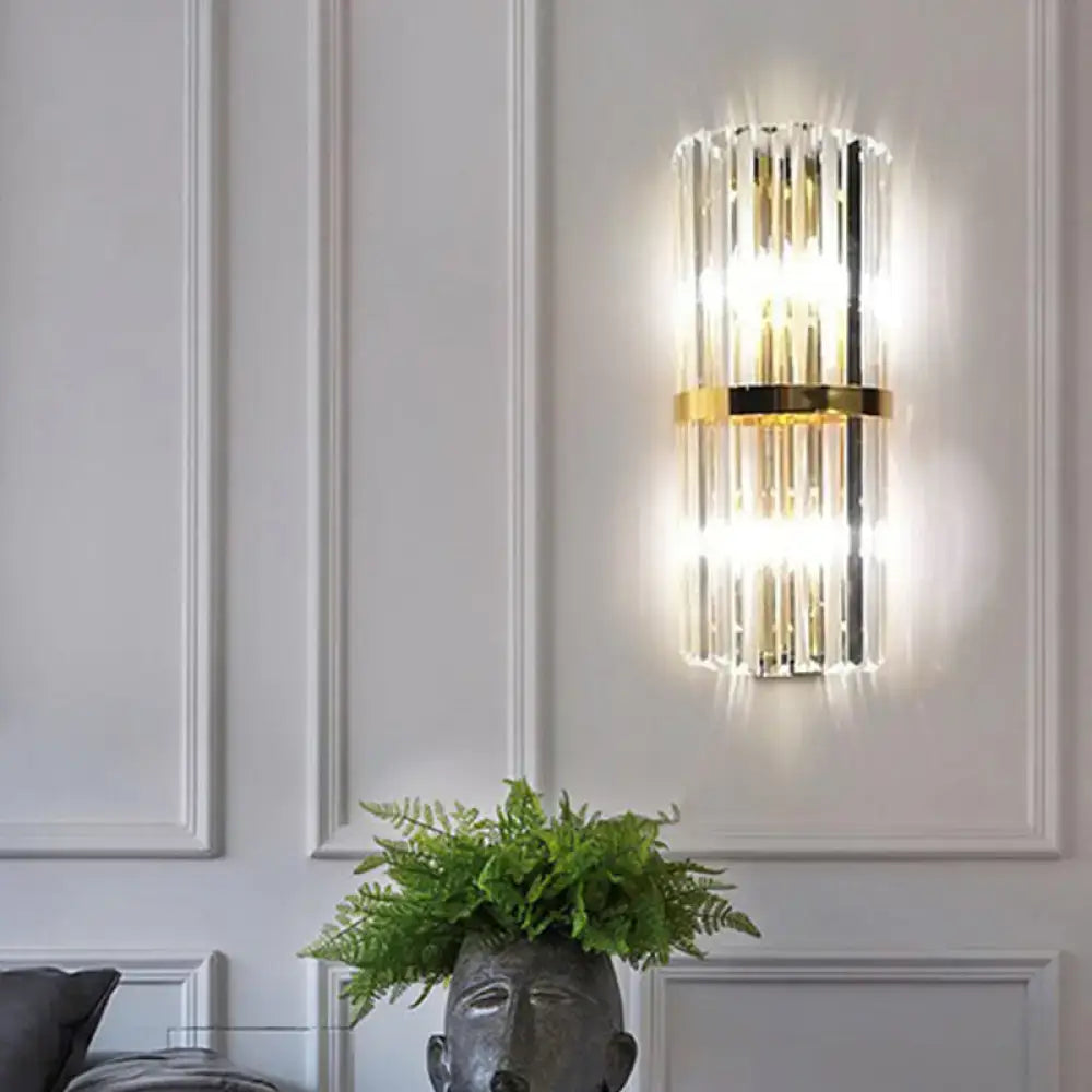 Modern gold crystal wall sconce with vertical rods and metal accents emitting warm glow for 110v-120v living space