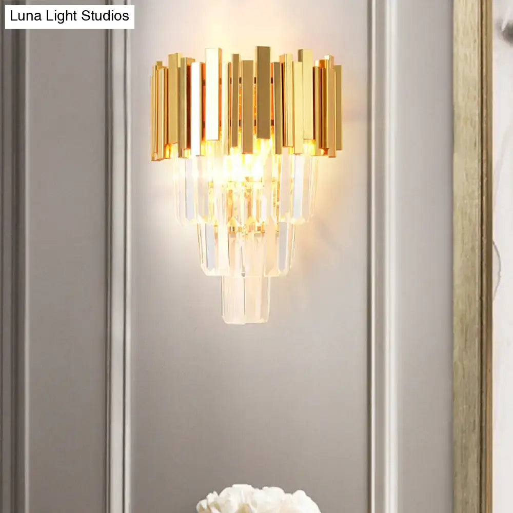 Modern gold crystal wall sconce featuring vertical metallic bars and cascading clear crystal prisms for living room use