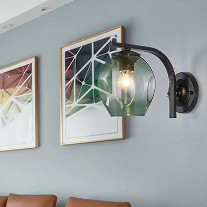Modern gold curved arm glass wall sconce with blue green translucent globe and exposed filament bulb for bedroom lighting