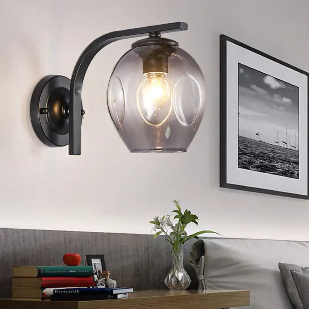A sleek black metal wall sconce with a curved arm and translucent gray glass globe for bedroom lighting