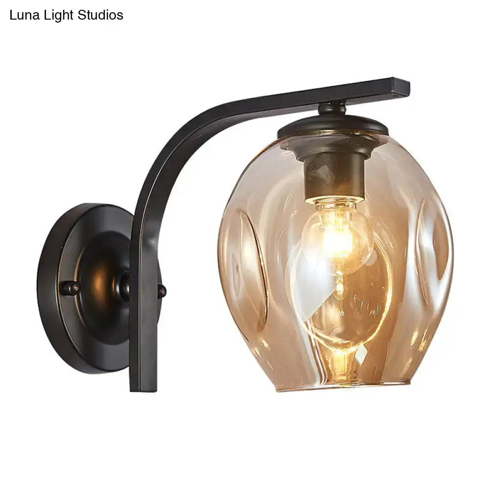 Modern gold curved arm glass wall sconce with warm amber textured globe and black metal mounting for bedroom lighting