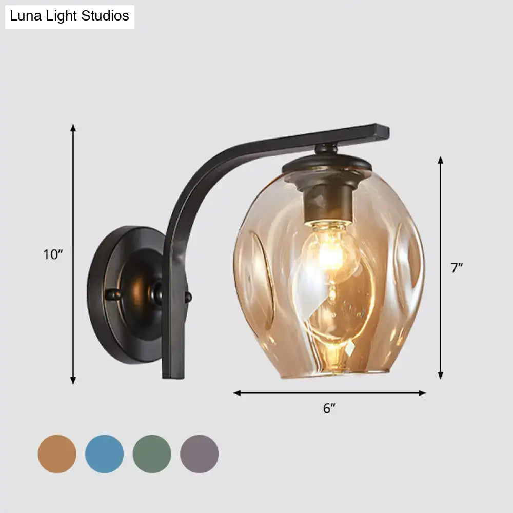 Modern gold curved arm glass wall sconce with warm amber textured globe and black metal mount for bedroom lighting
