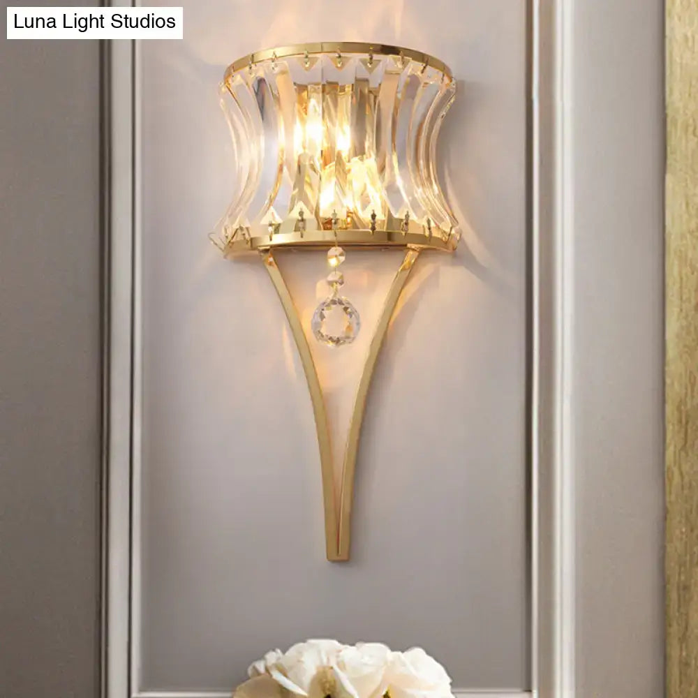 Modern gold curved wall light featuring a clear crystal prism shade and dangling crystal accents for bedroom use