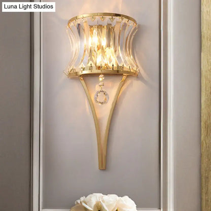 Modern gold curved wall light featuring a clear crystal prism shade and dangling crystal accents for bedroom use