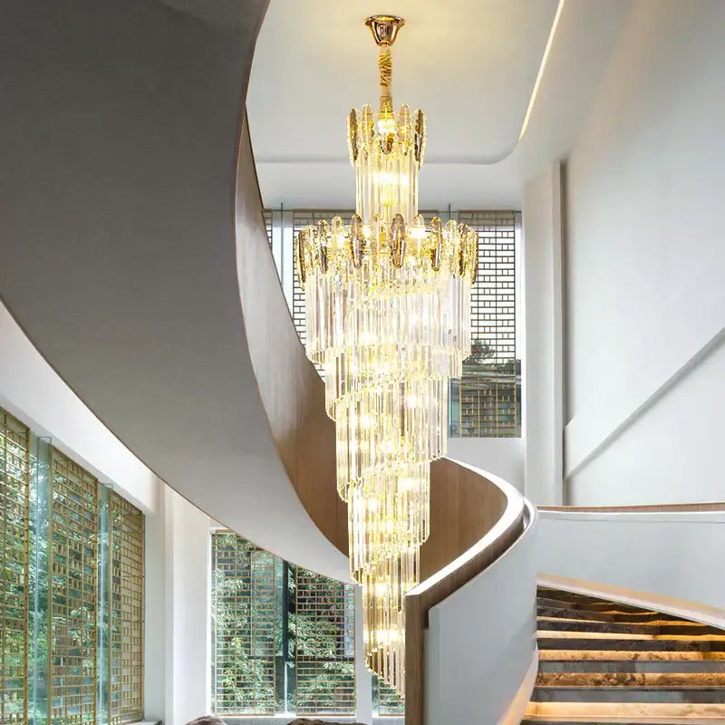 A modern gold decorbites crystal chandelier with multi-tiered crystals hangs above a spiral staircase living room