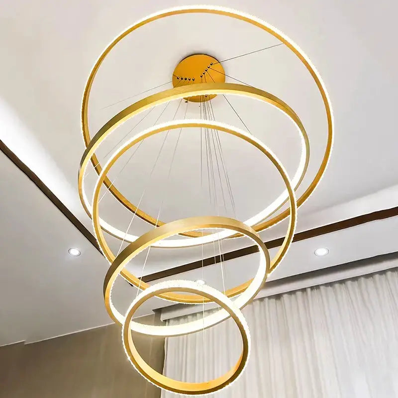 Modern gold-toned decorbites crystal chandelier with illuminated cascading rings for staircase and living room lighting