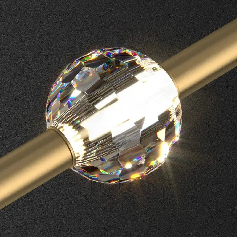 A faceted clear crystal ball with rainbow reflections in a modern gold decorbites crystal led chandelier pendant light