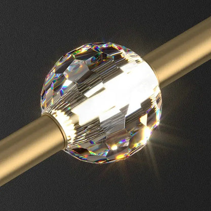 A faceted clear crystal ball with rainbow reflections in a modern gold decorbites crystal led chandelier pendant light