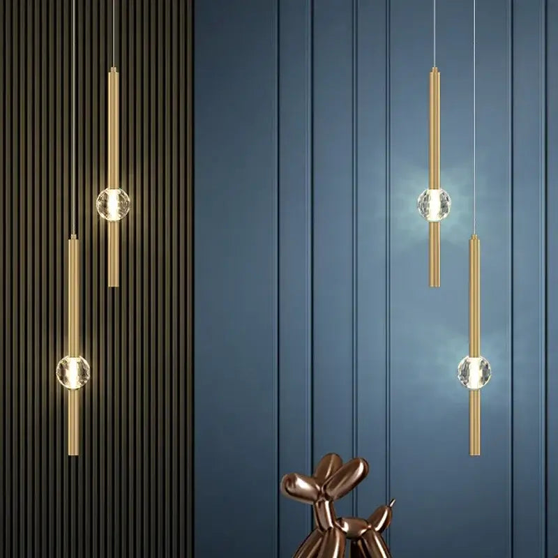 Modern gold decorbites crystal led chandelier featuring gold-toned cylindrical pendants with clear crystal spheres