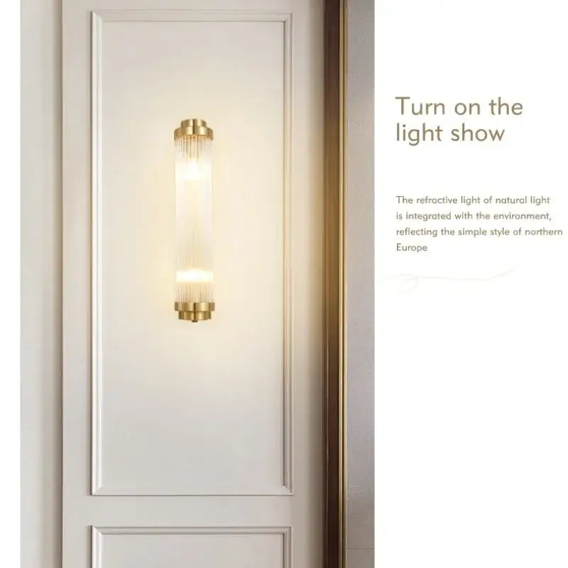 Modern gold decorbites crystal wall sconce with cylindrical glass body and vertical ridges emitting warm light