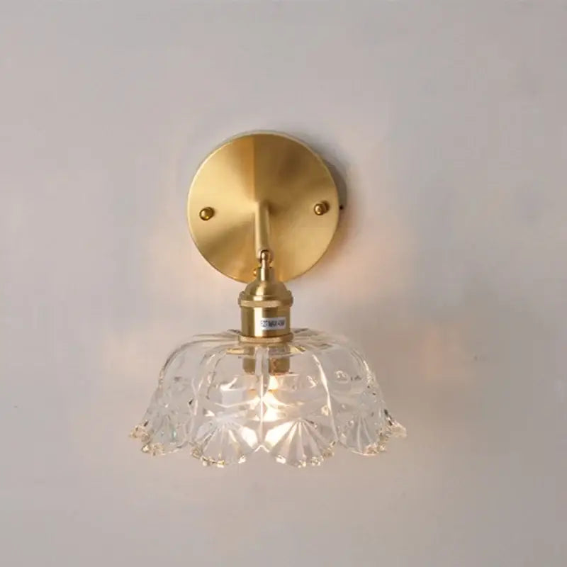 Modern gold faceted clear glass wall lamp with brass mounting plate and stem for bedroom wall light