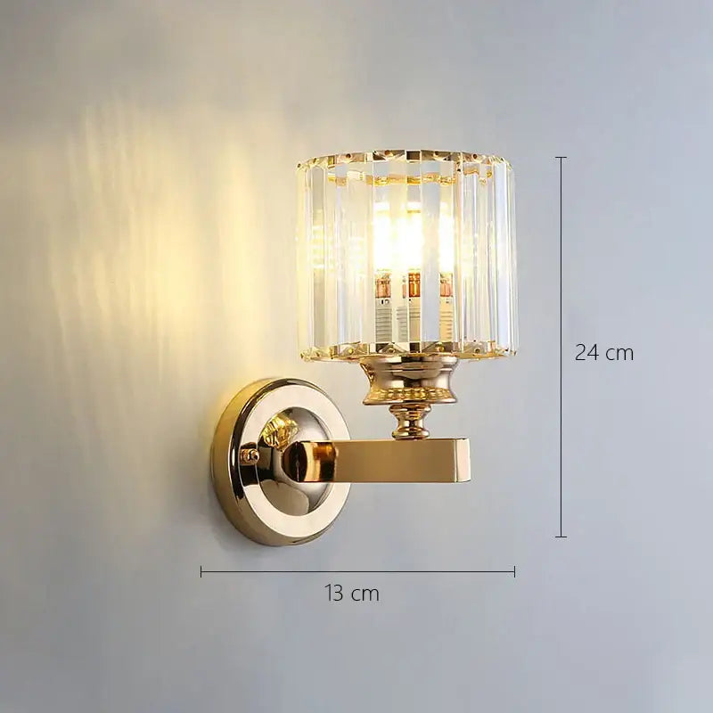 Modern gold wall lamp with cylindrical faceted glass shade and three exposed bulbs for living room sconce
