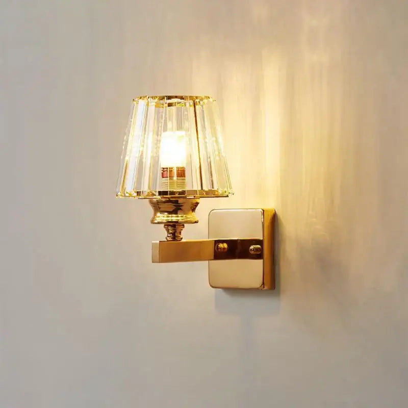 Modern gold wall lamp with faceted glass shade designed as a living room glass shade wall sconce
