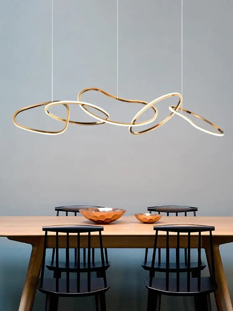 Modern gold flowing ring led decorbites elegant chandelier with interlocking circular rings above dining table
