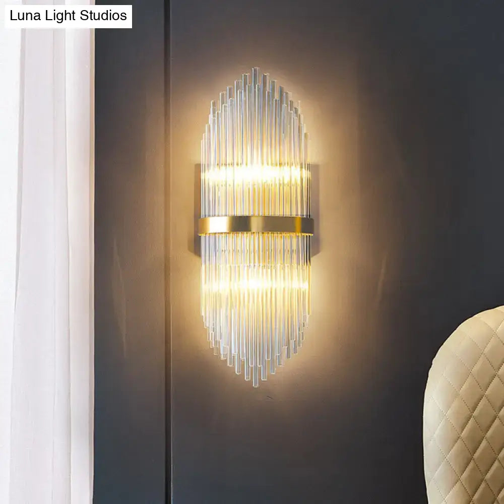 Modern gold flute shaped wall sconce with clear crystal rods and polished metal accents for bedroom lighting