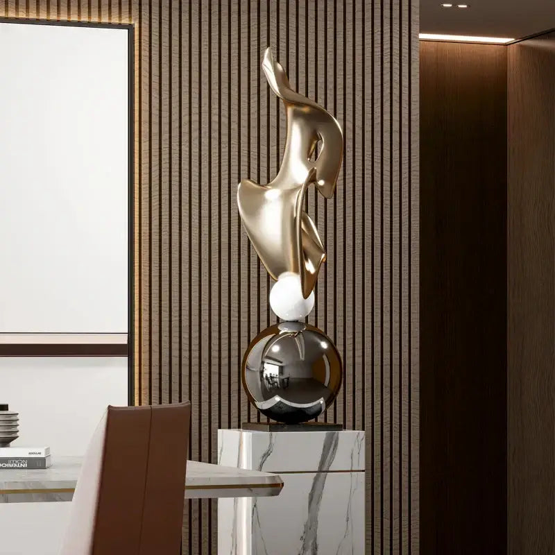 A sleek gold geometric electroplating art sculpture with flowing curves on a marble pedestal for living room decorbites