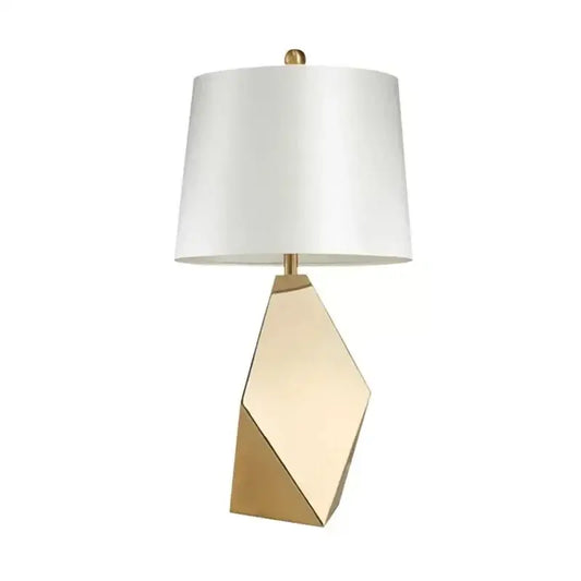 Modern gold geometric table lamp with a sleek faceted base and white drum shade for bedroom nightstand lighting