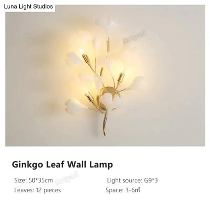Modern gold ginkgo leaf porcelain wall sconce with 12 translucent white leaves and gold-toned metal stems emitting warm glow