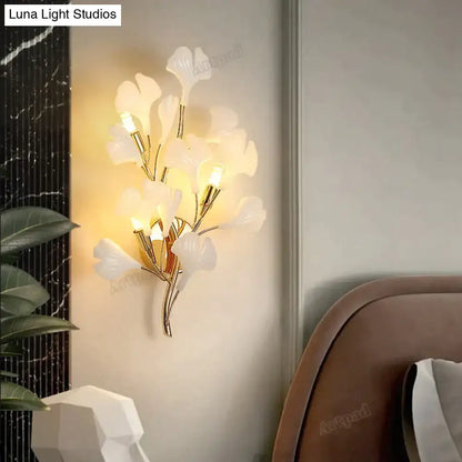 Modern gold ginkgo leaf porcelain wall sconce with elegant white leaves and gold-toned metal branches for bedroom lighting