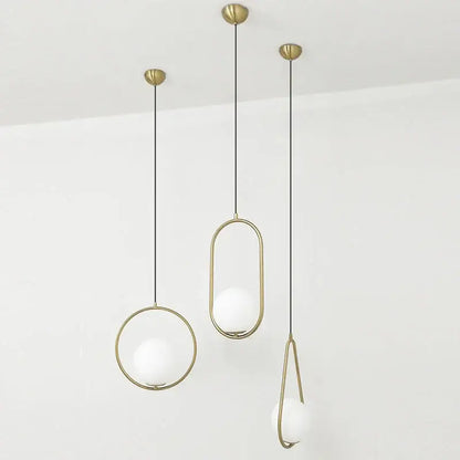 Three modern pendant lights with brass frames and frosted glass balls suspended by black cords for dining room decorbites glass ball pendant