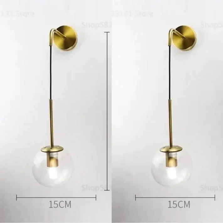 Modern gold glass ball wall lamp with a clear glass globe and slender brass stem for elegant bedroom decorbites wall lamp