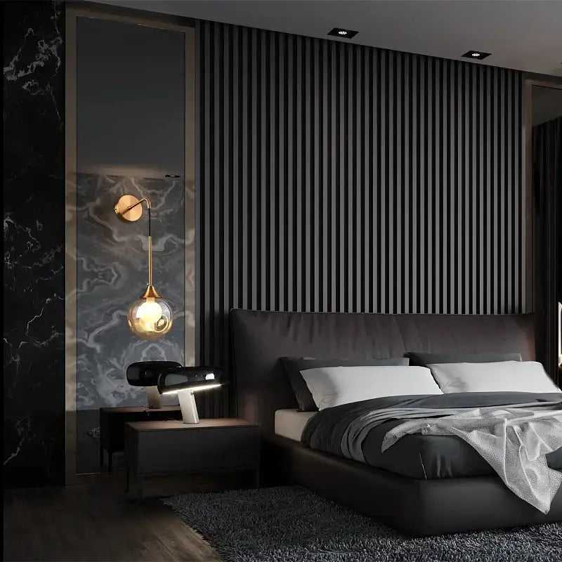 Modern gold glass ball wall sconce with teardrop lamp mounted above black leather headboard with white pillows and gray bedding