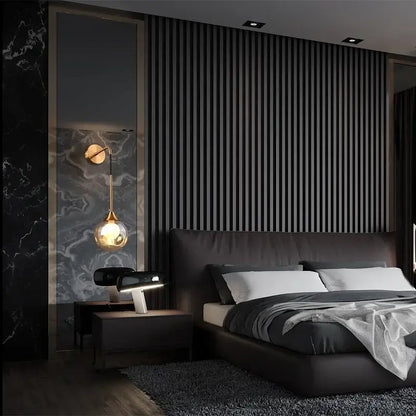 Modern gold glass ball wall sconce with teardrop lamp mounted above black leather headboard with white pillows and gray bedding
